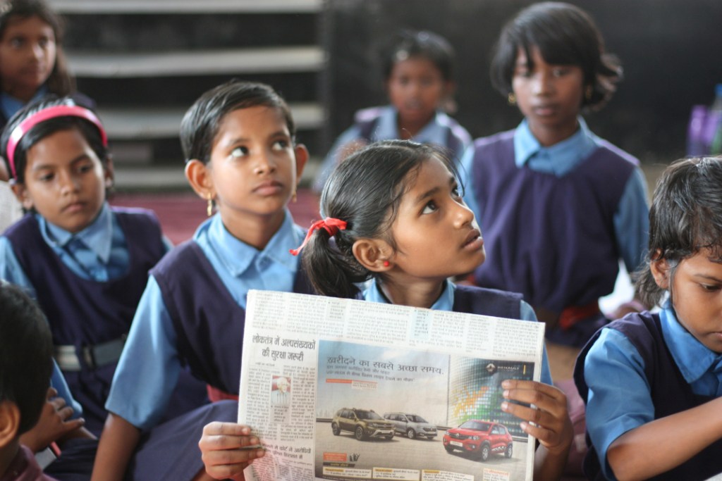 Girls with newspaper in class